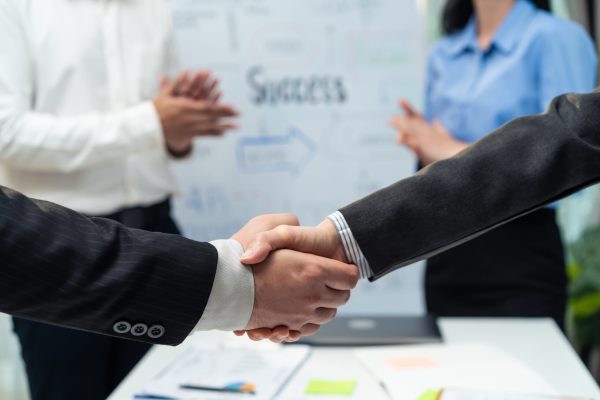 Close up hands of business people handshake after success negotiations. Employee worker team clap hand and enjoy partnership agreement, Business deal merger and acquisitionto in company meeting room.
